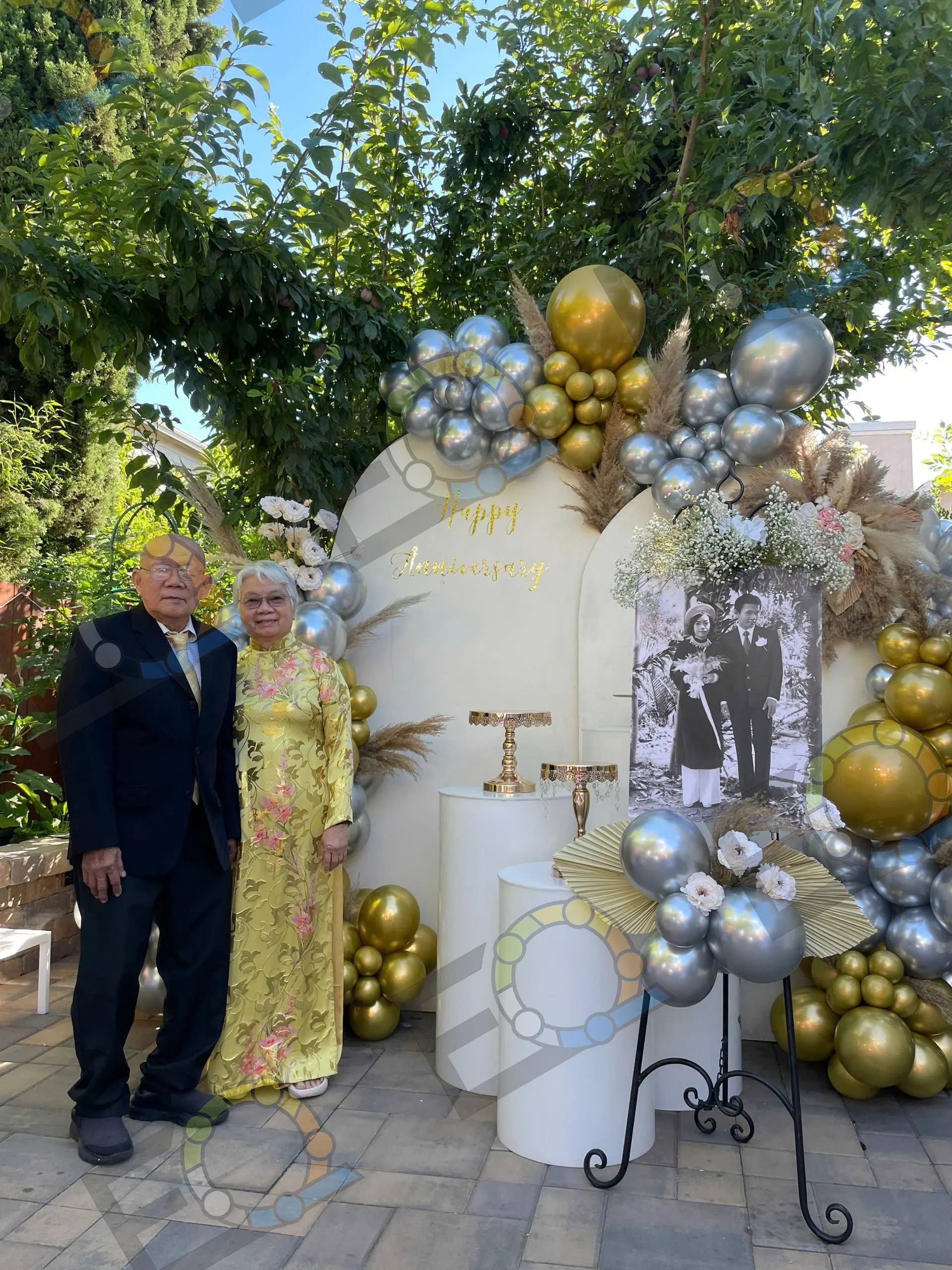 A couple beside a gold and silver anniversary backdrop