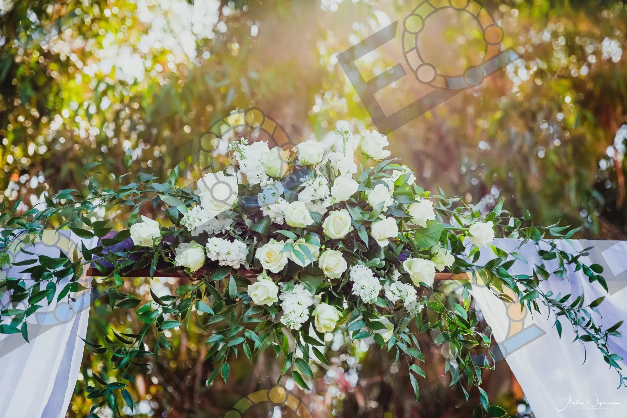 A swag of white roses and greenery across a ceremony arch