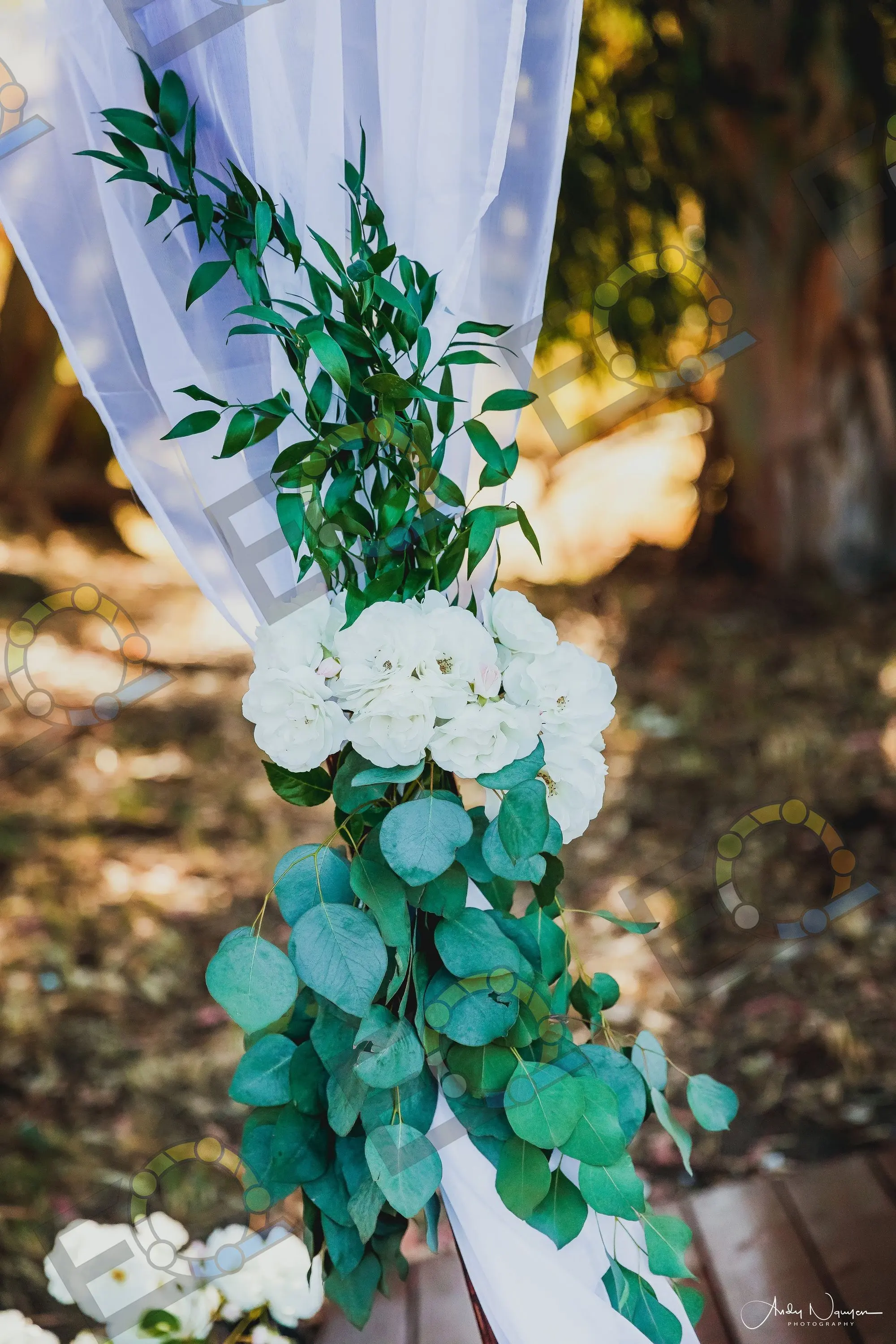 White roses and eucalyptus wound down a draped arch
