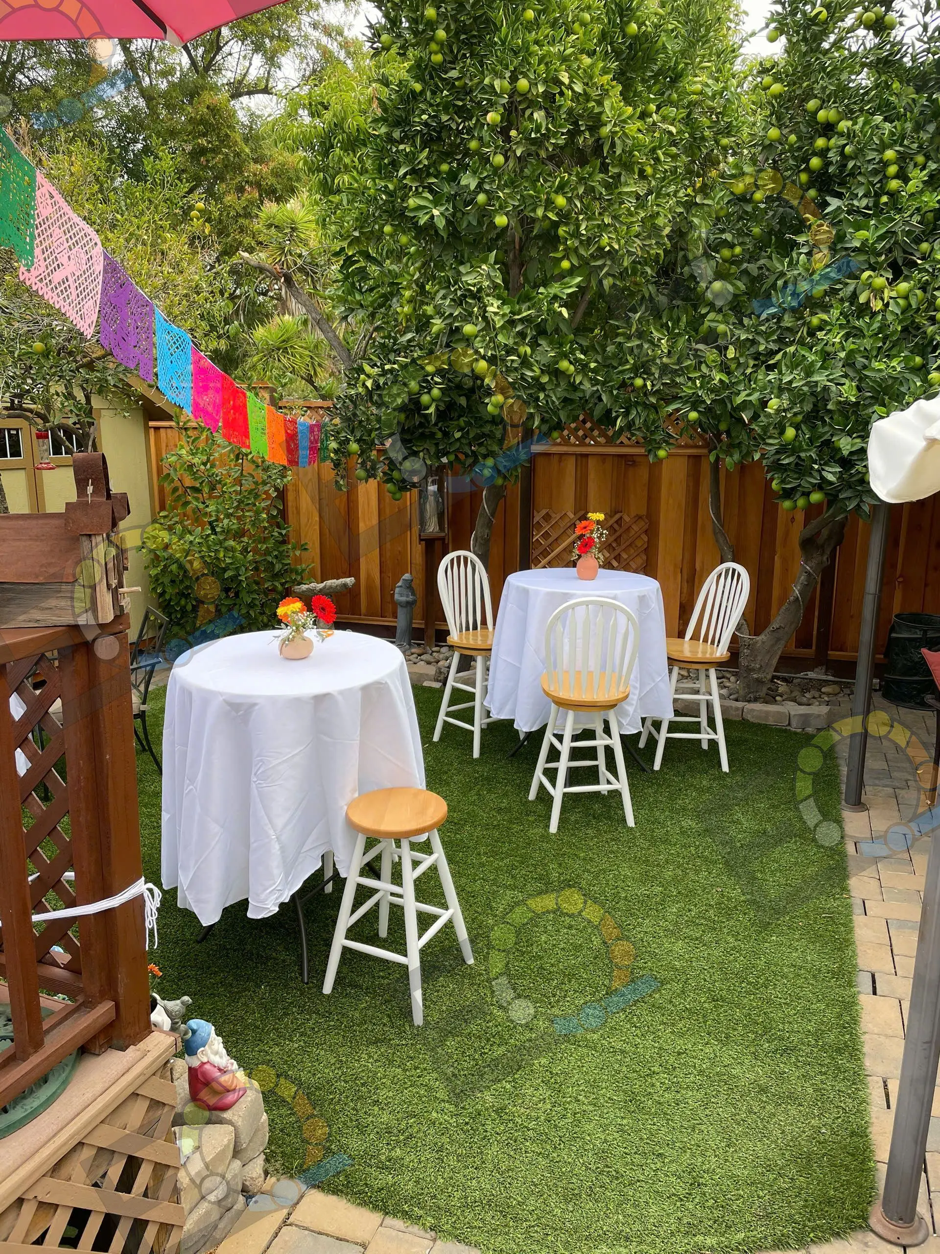A white cocktail table on a lawn strung with papel picado