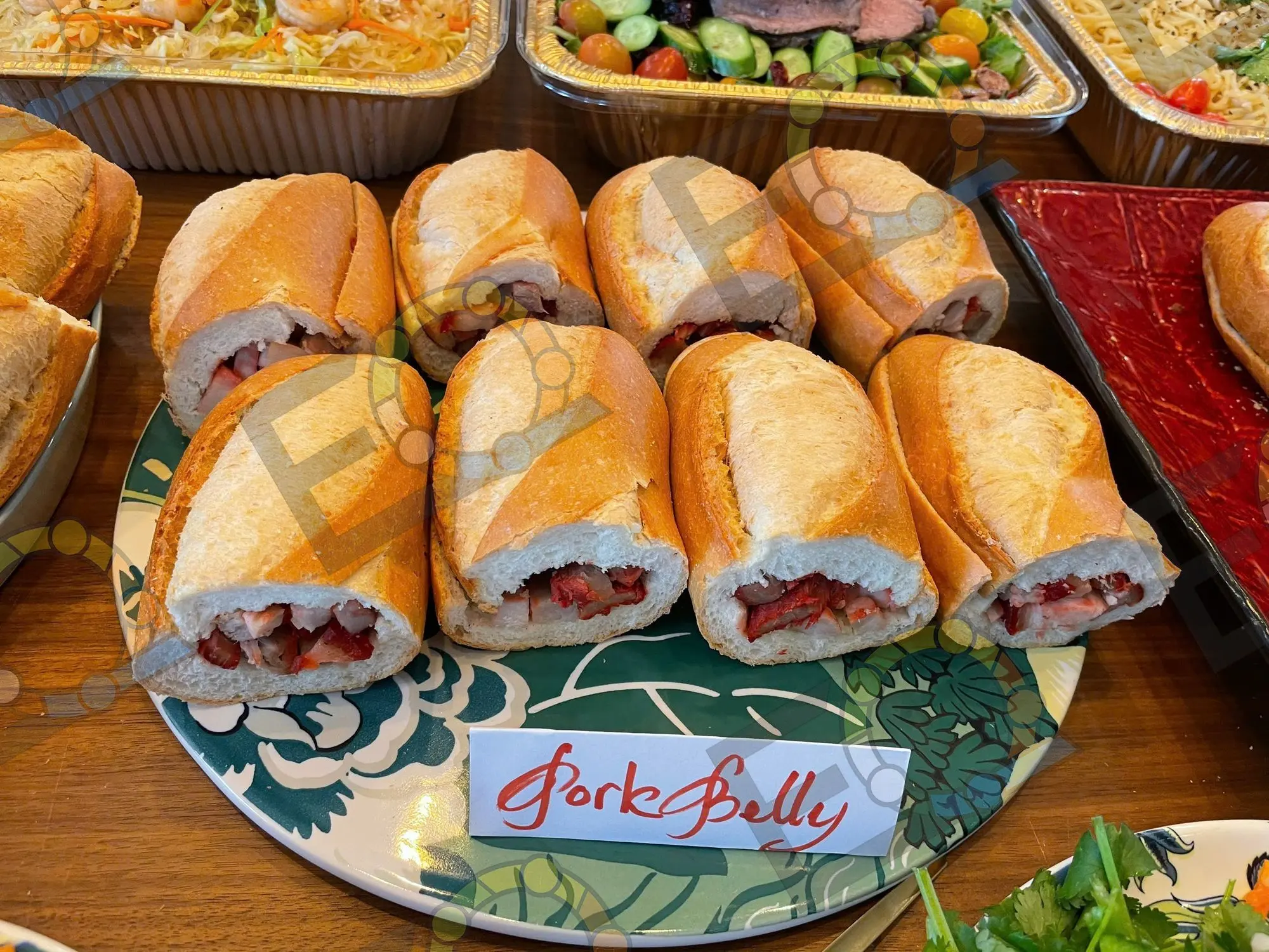 Banh mi sliced and stacked on a patterned platter beside a labelled menu card
