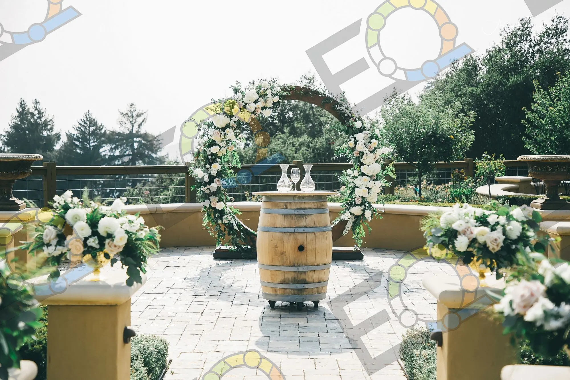 A circular floral arch behind a wine barrel