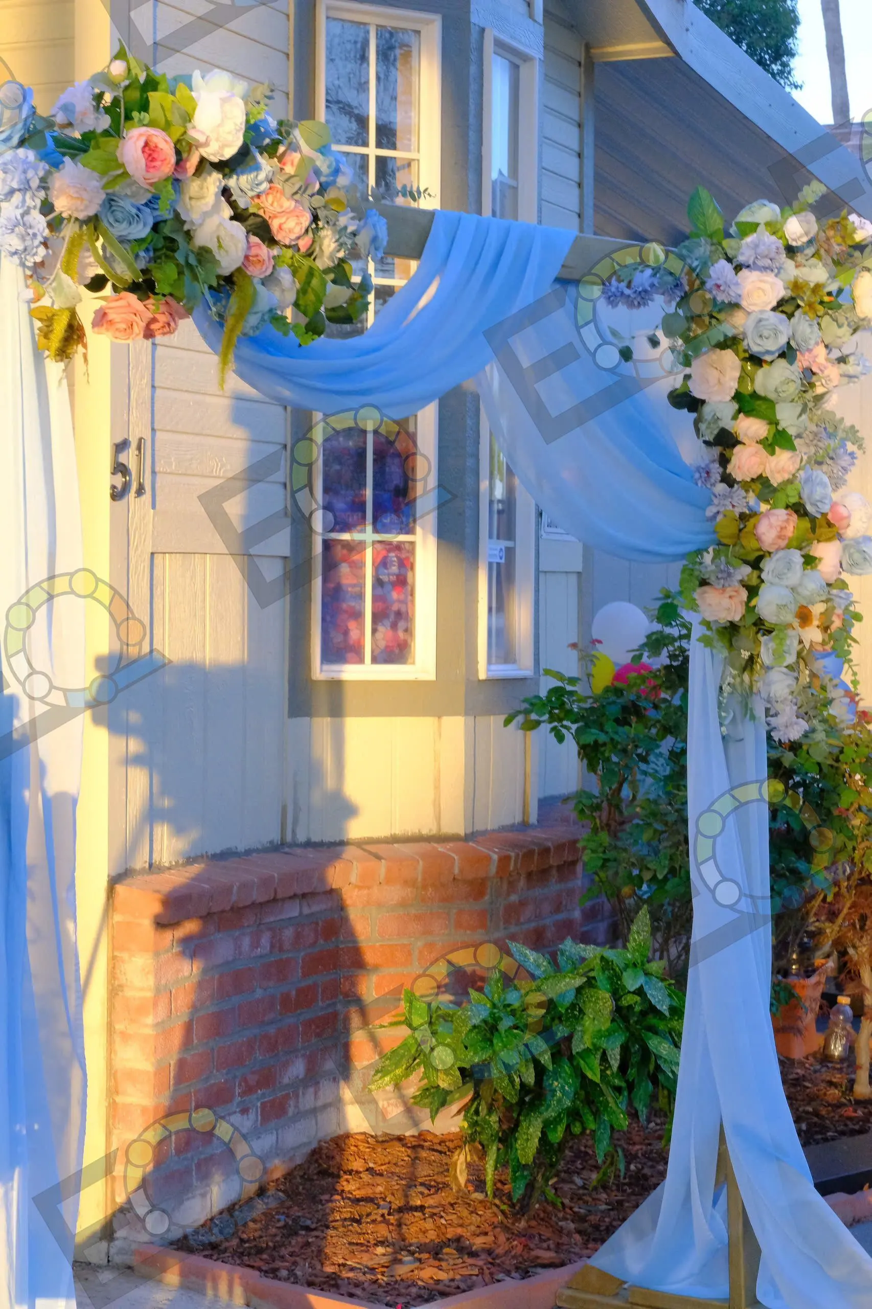 A doorway framed with blue draping and floral garlands