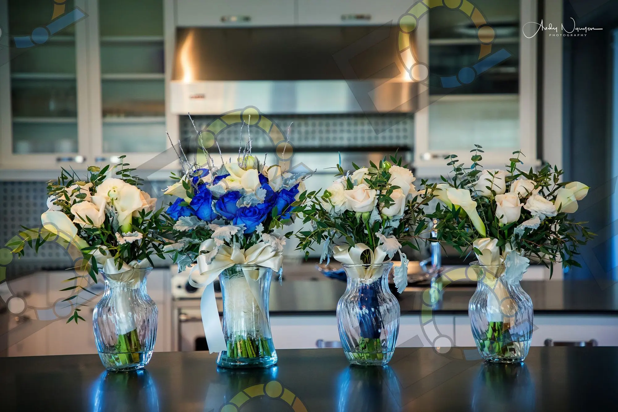 Blue and white arrangements in glass vases lined along a counter