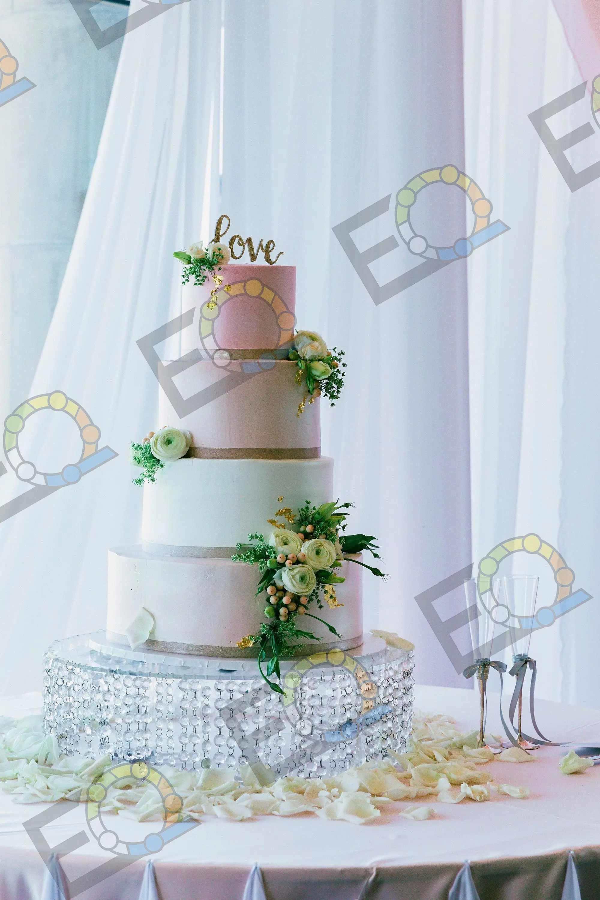A five-tier blush wedding cake trimmed with fresh flowers