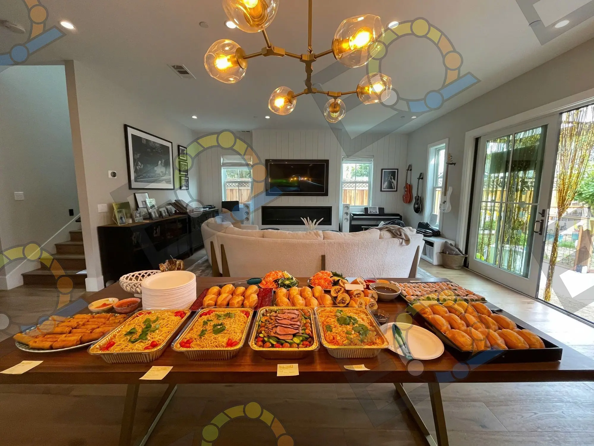 Trays of noodles, salads and pastries set out along a table in a bright room