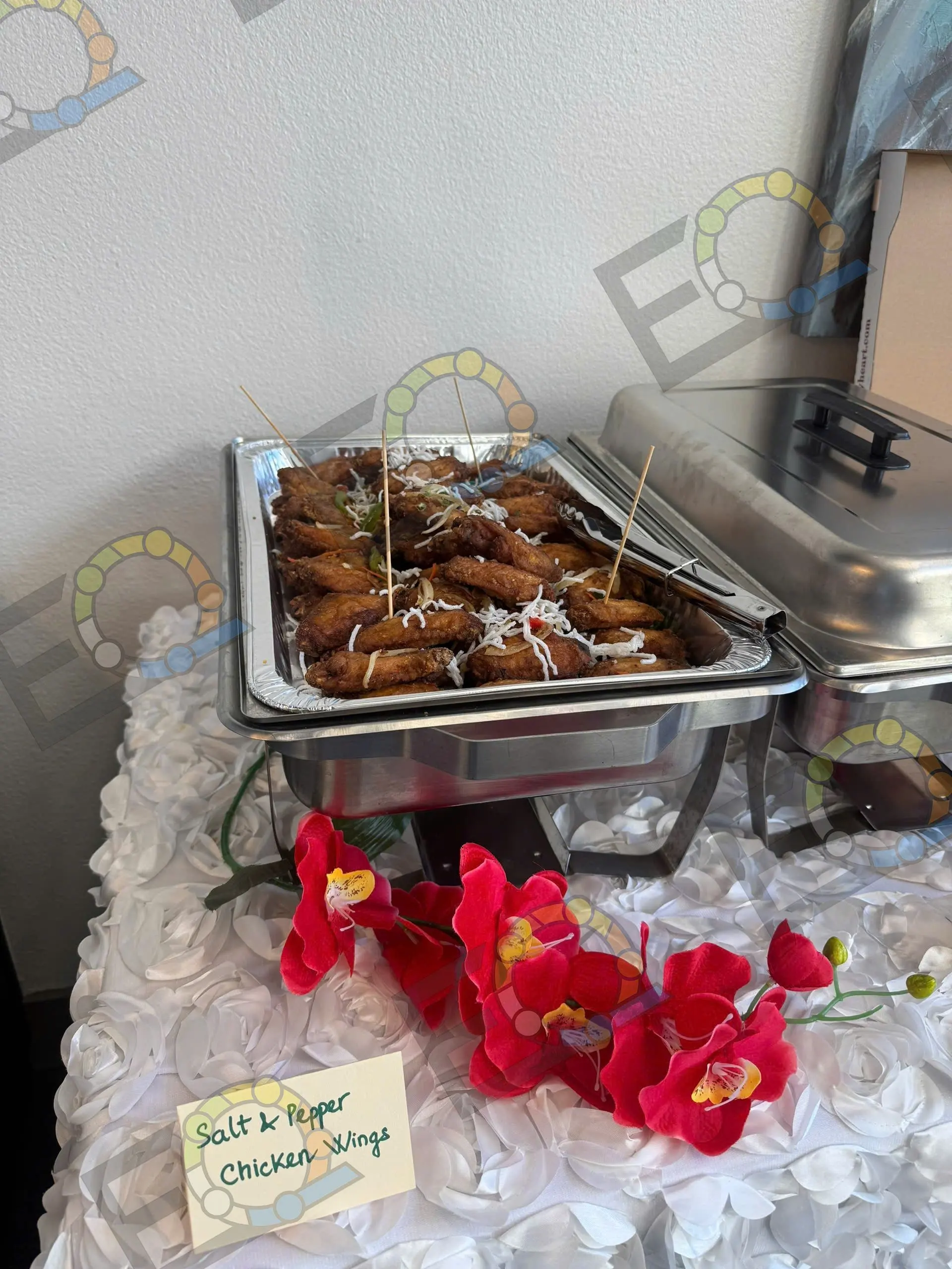 Salt and pepper chicken wings in a chafing dish beside red poinsettias