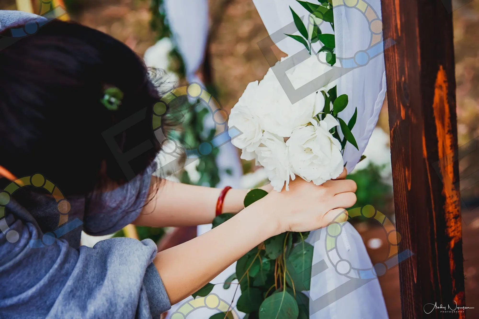 Tying a chiffon sash and white bloom to a ceremony chair