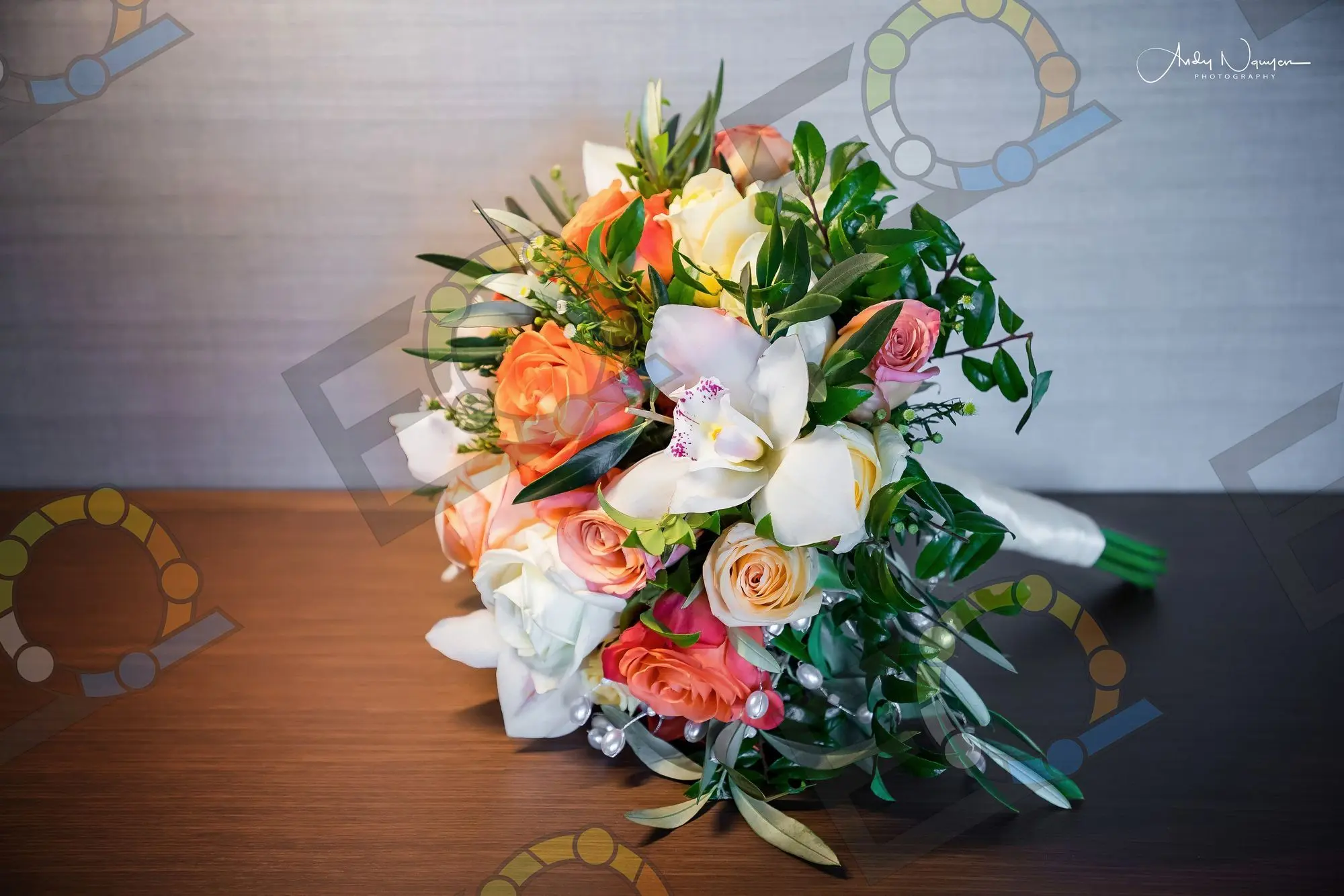 A bouquet of coral roses, orchids and olive leaves