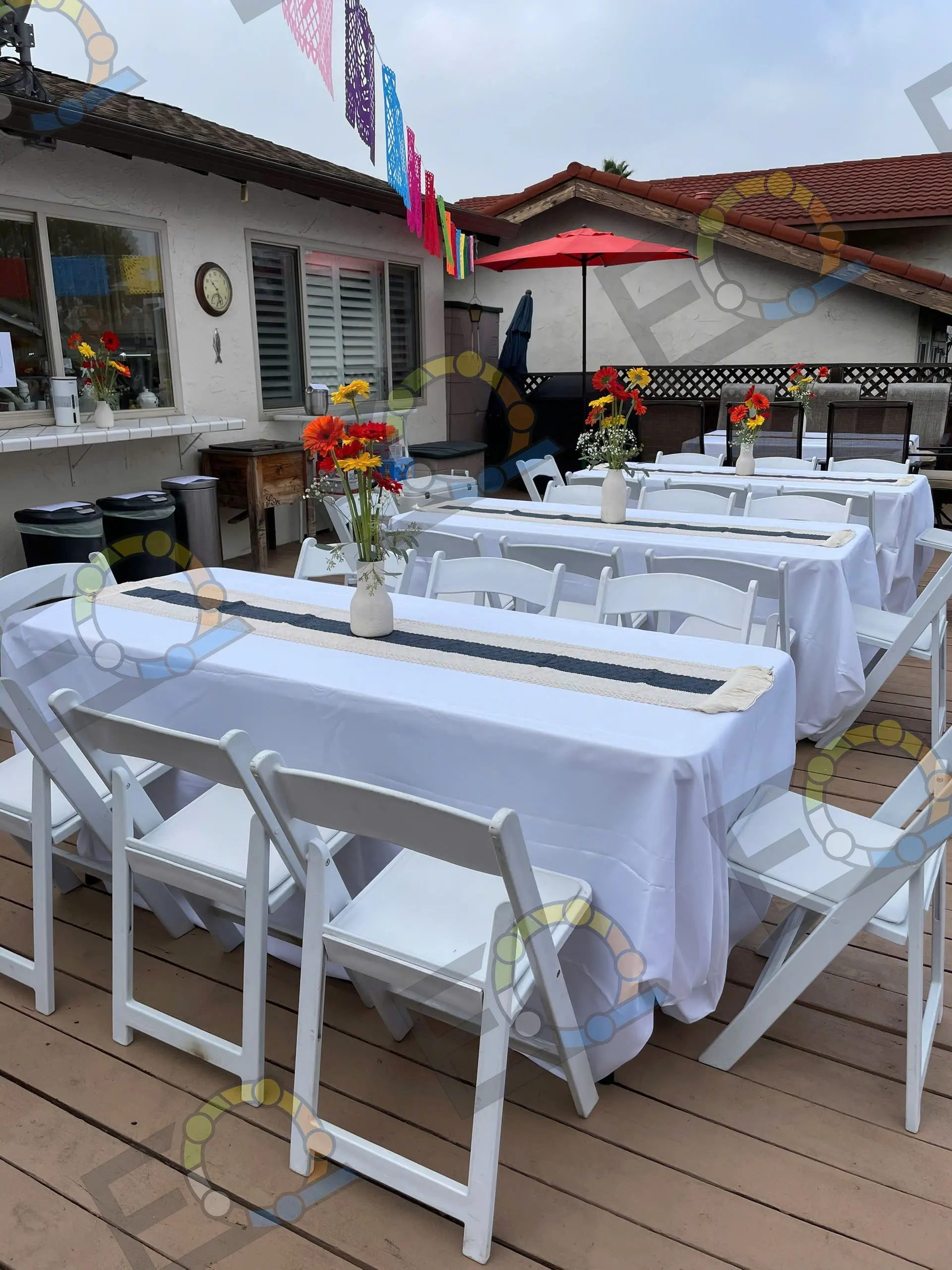 Long tables dressed in white linen on a garden deck