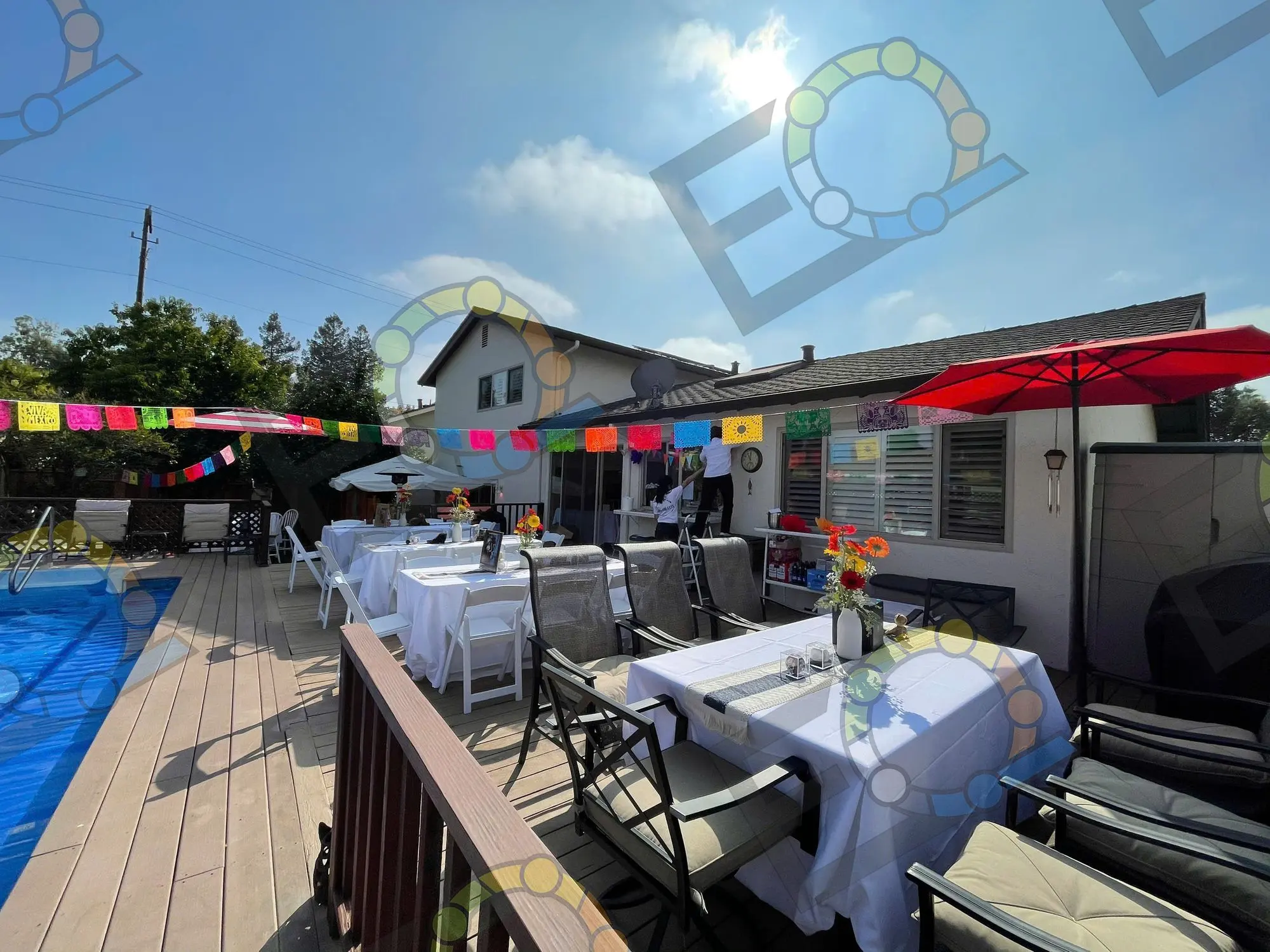 Long tables dressed in white on a deck hung with bunting