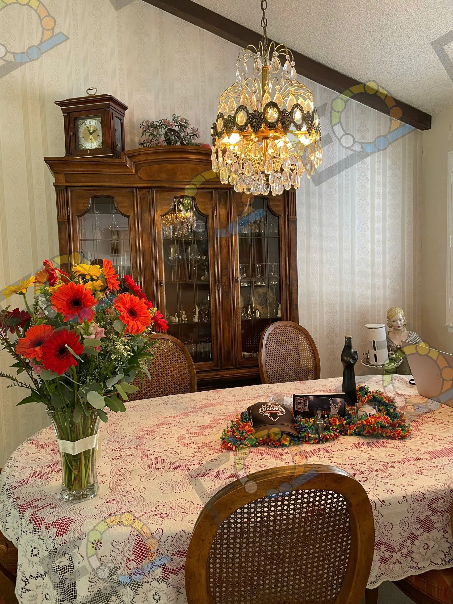 A tall gerbera and sunflower arrangement on a dining table