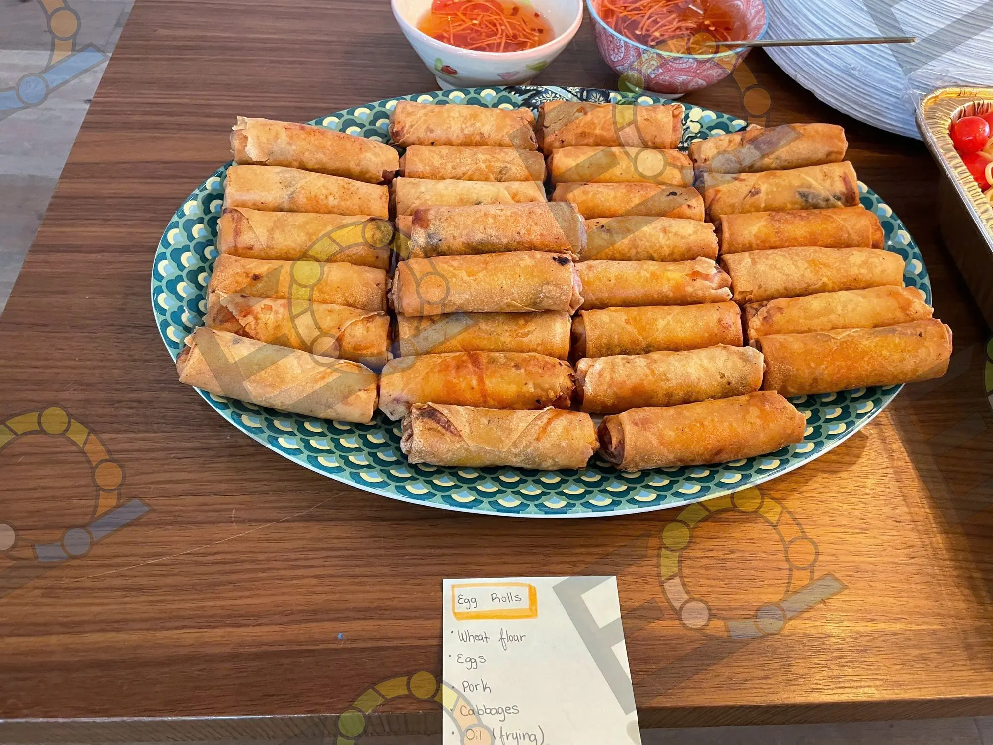 A platter of egg rolls beside bowls of dipping sauce