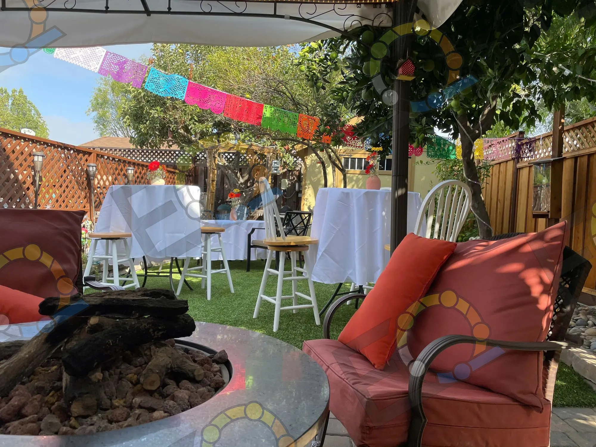 Cocktail tables beside a stone fire pit under a canopy