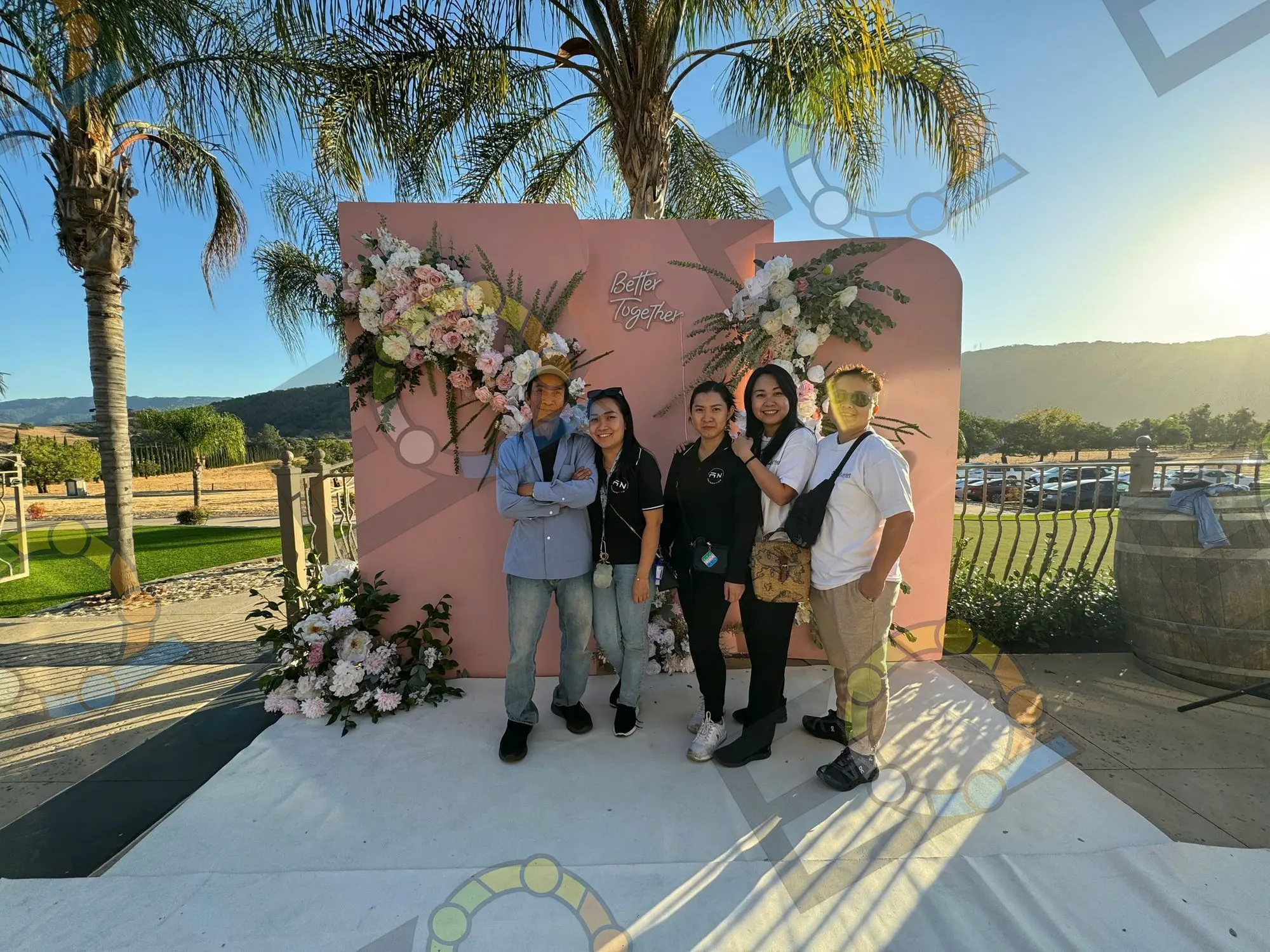 Guests posing at a blush floral photo backdrop