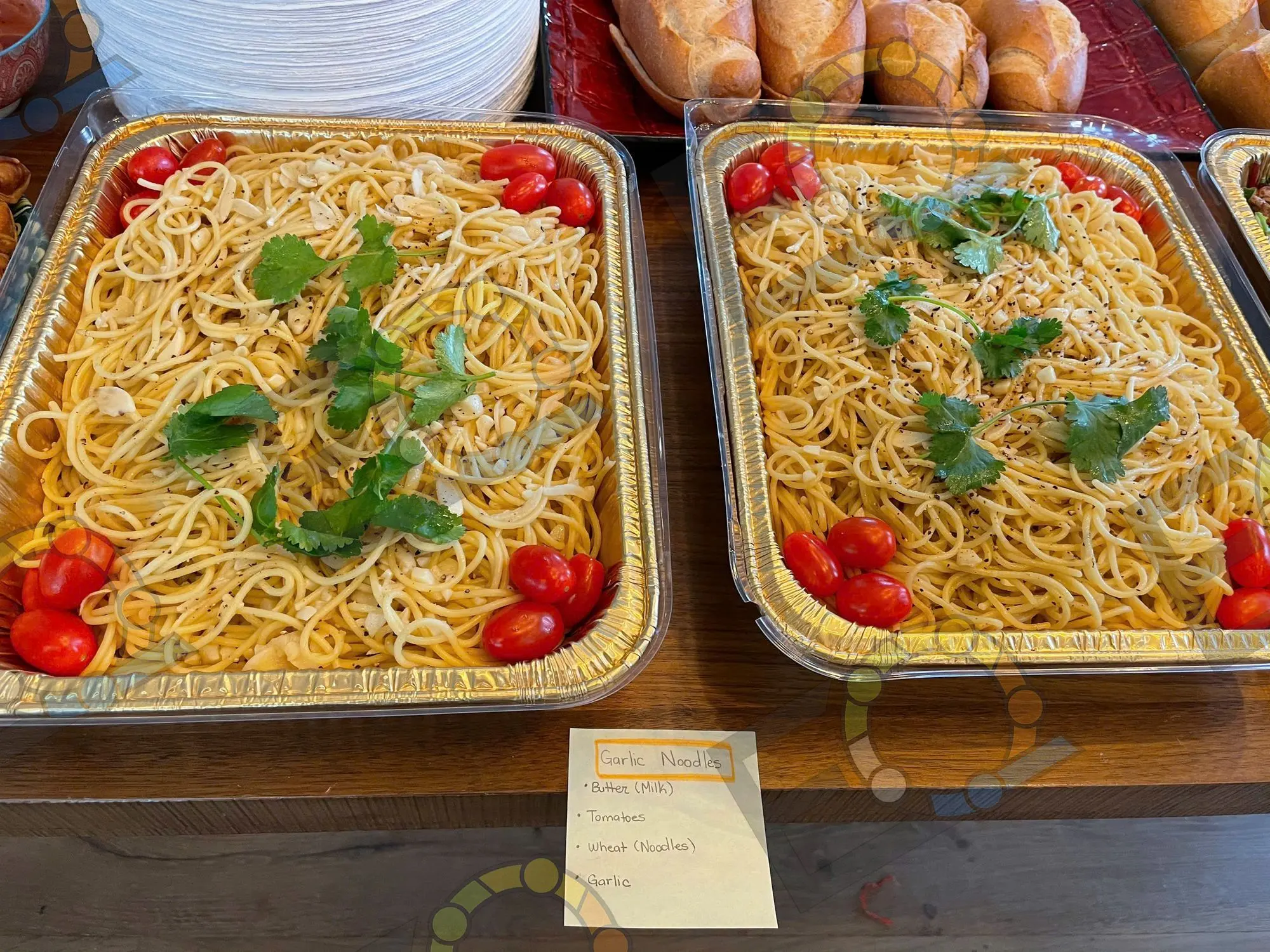 Foil trays of garlic noodles labelled for a buffet