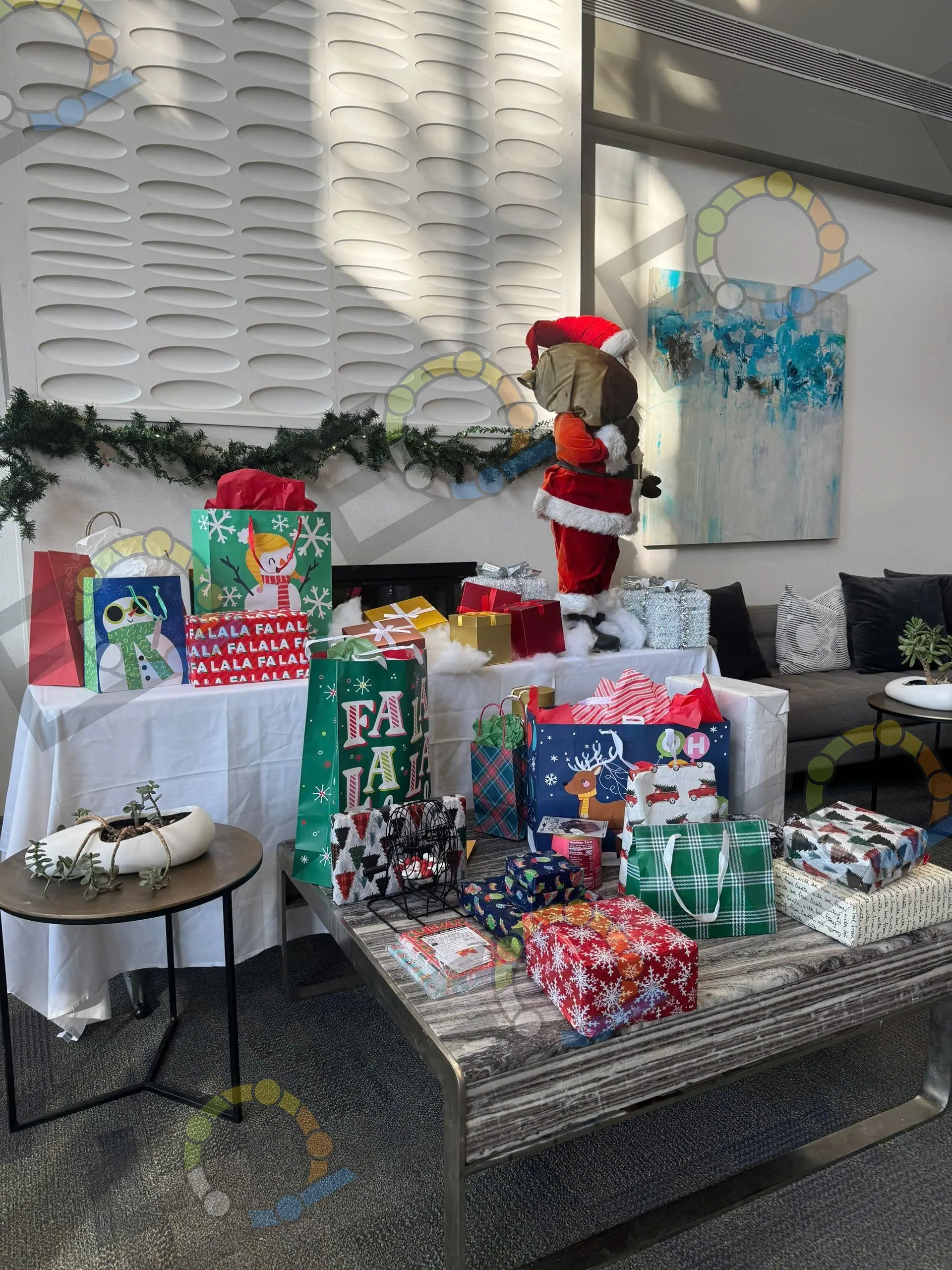 A holiday gift table with wrapped presents, garland and a Santa figure