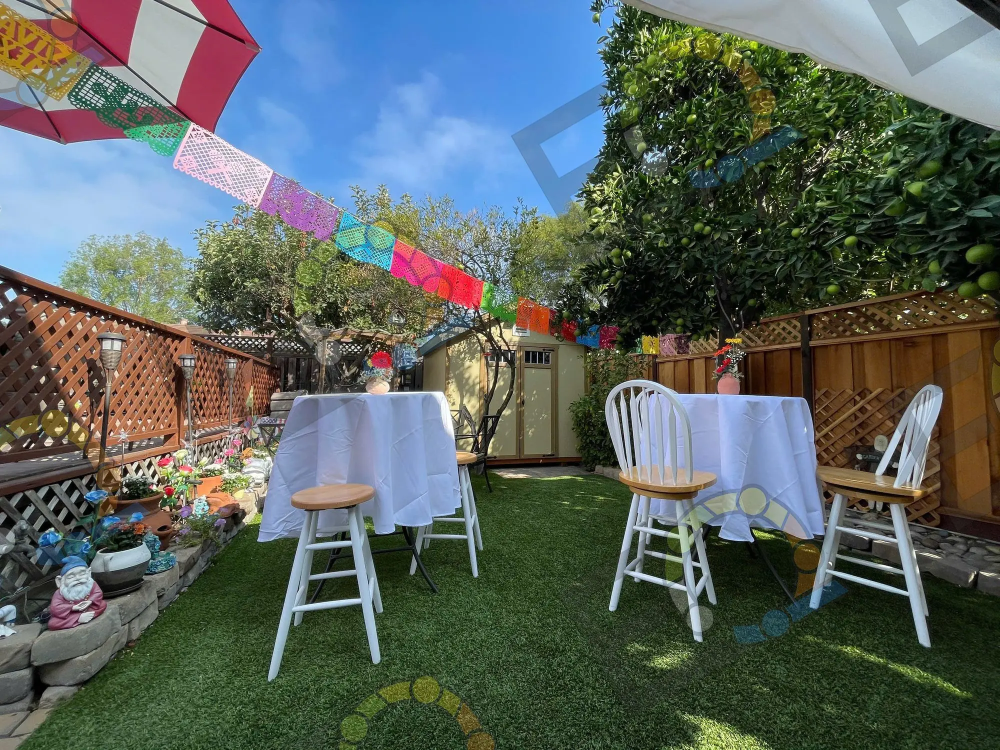Cocktail tables and stools on a lawn hung with papel picado