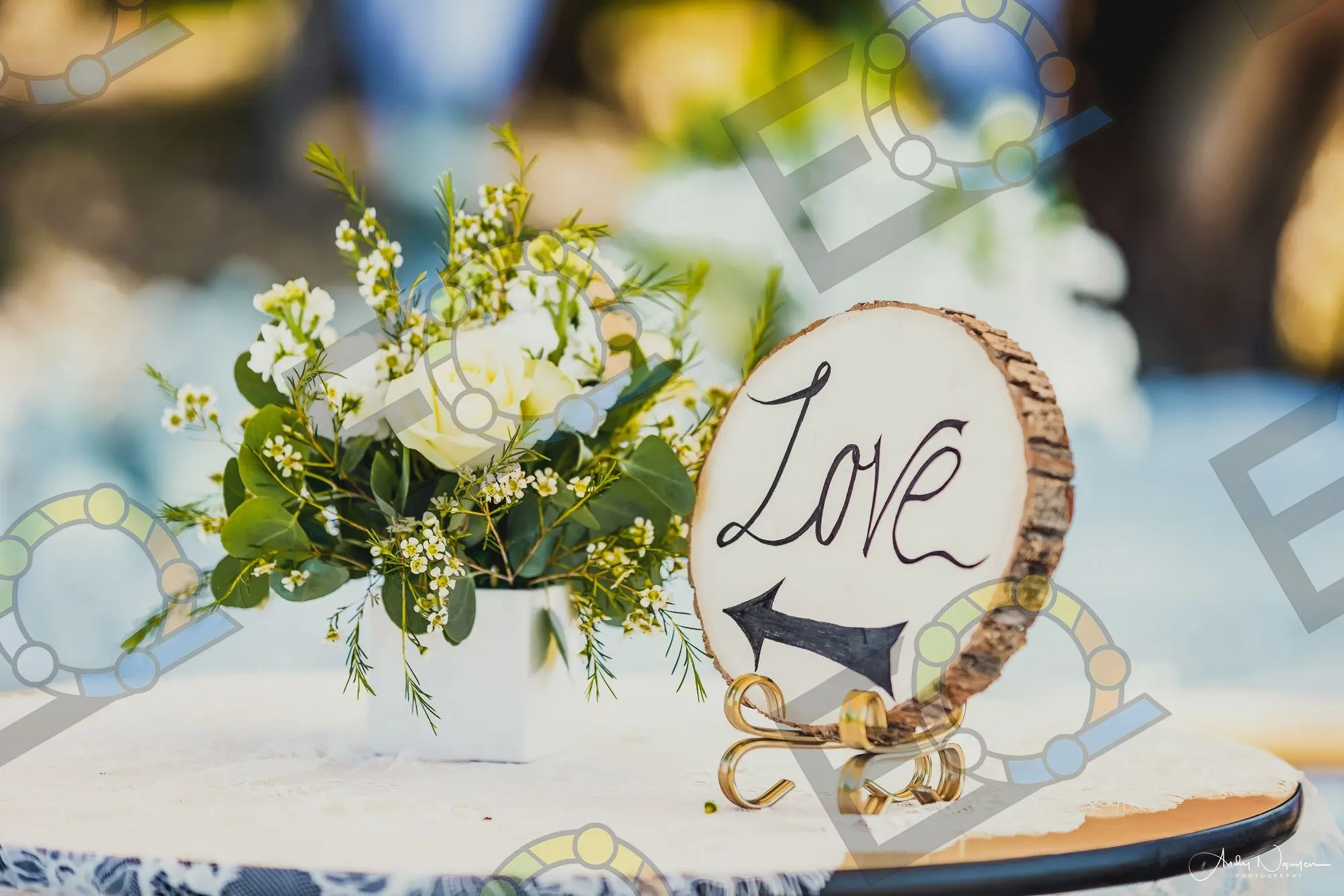 A wooden Love sign resting against white roses