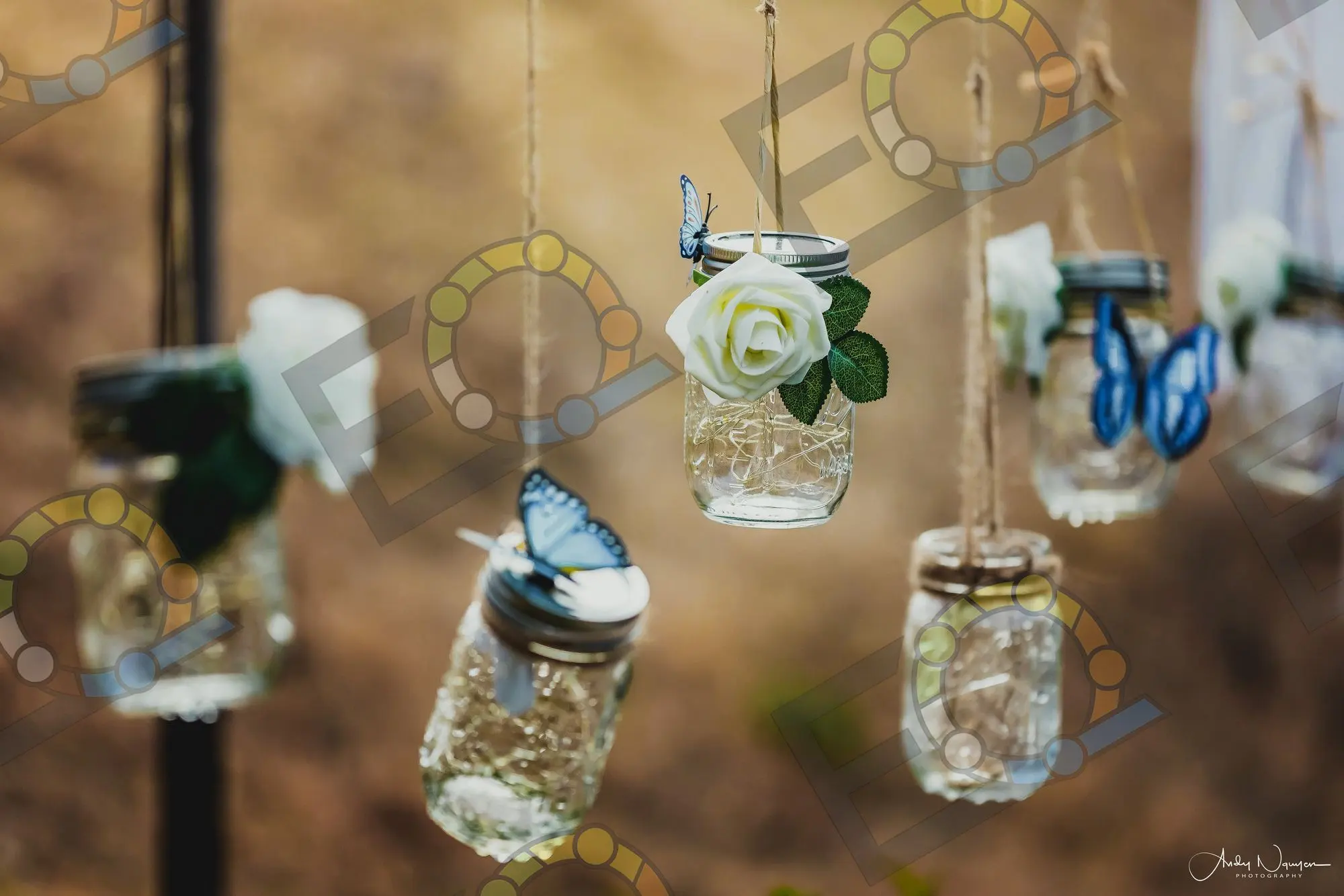 Mason jar lanterns and paper butterflies hung on a hillside