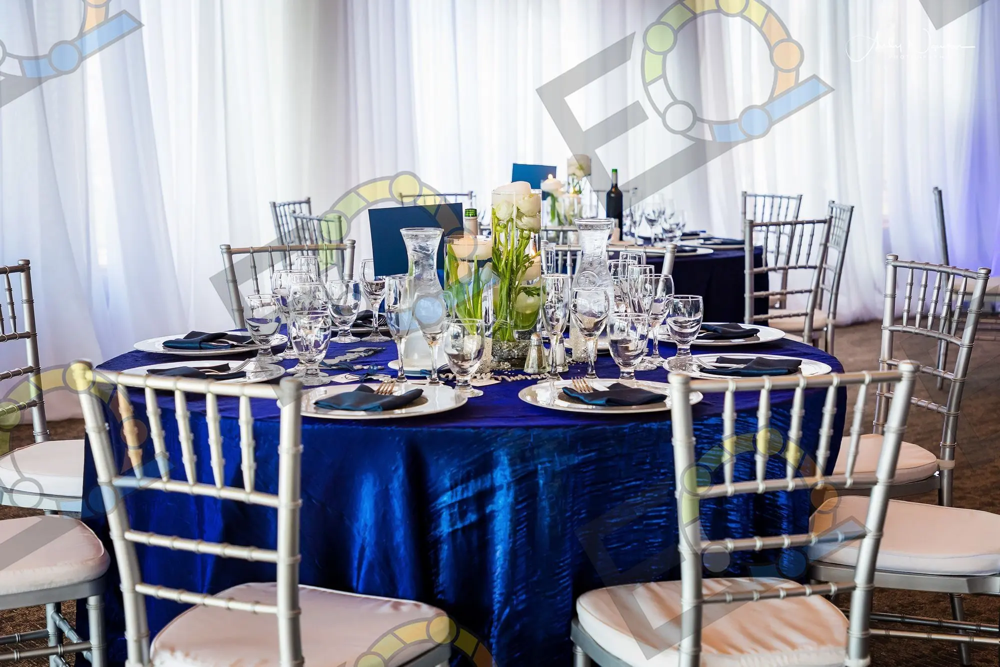 Navy tables set in front of white draping