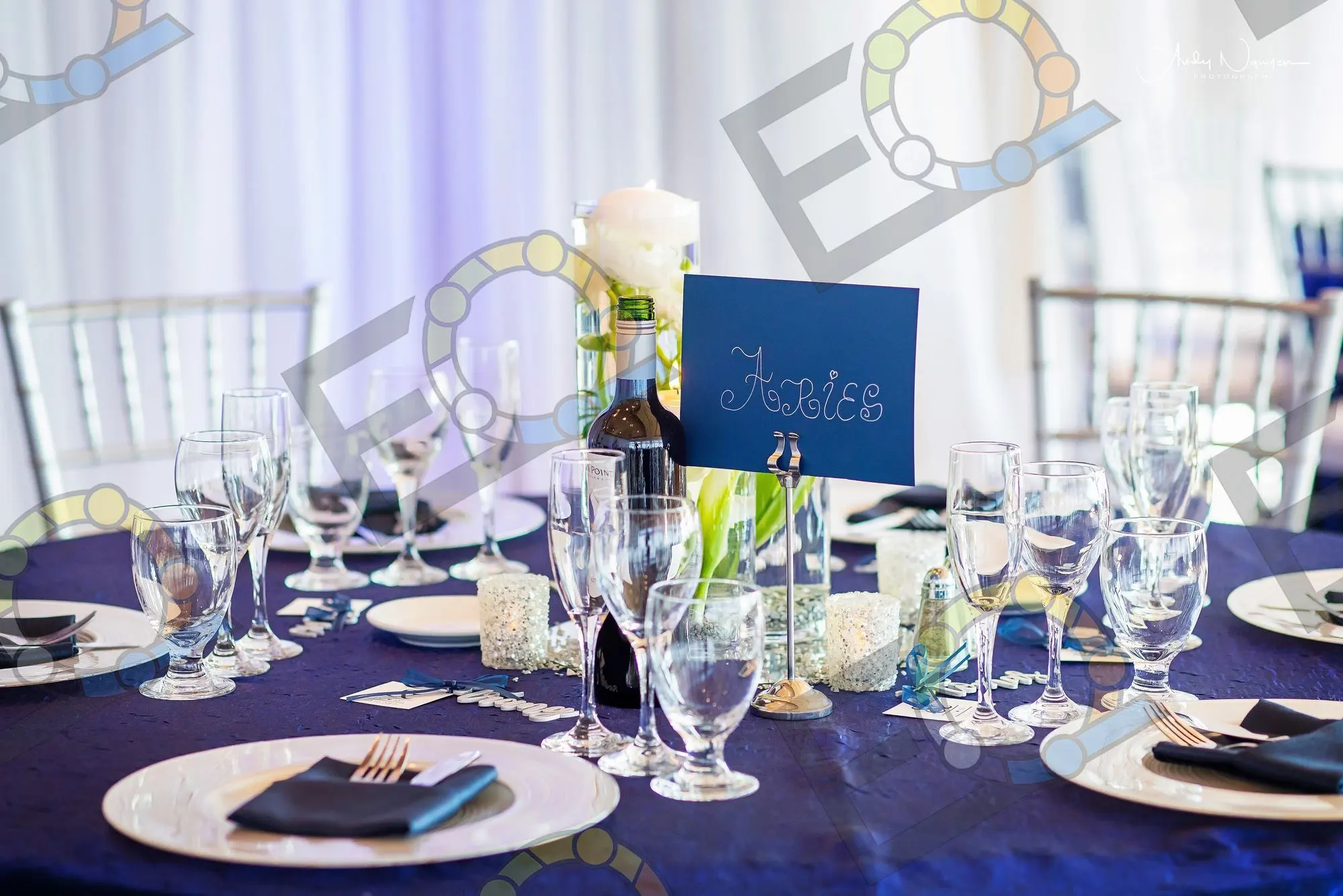 A navy tablescape with pillar candles and blue table numbers