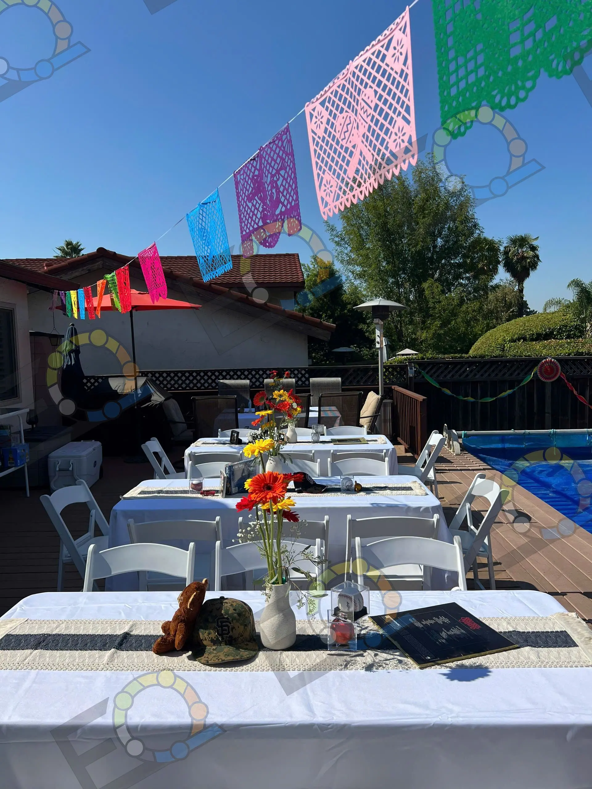 A poolside dinner table beneath papel picado