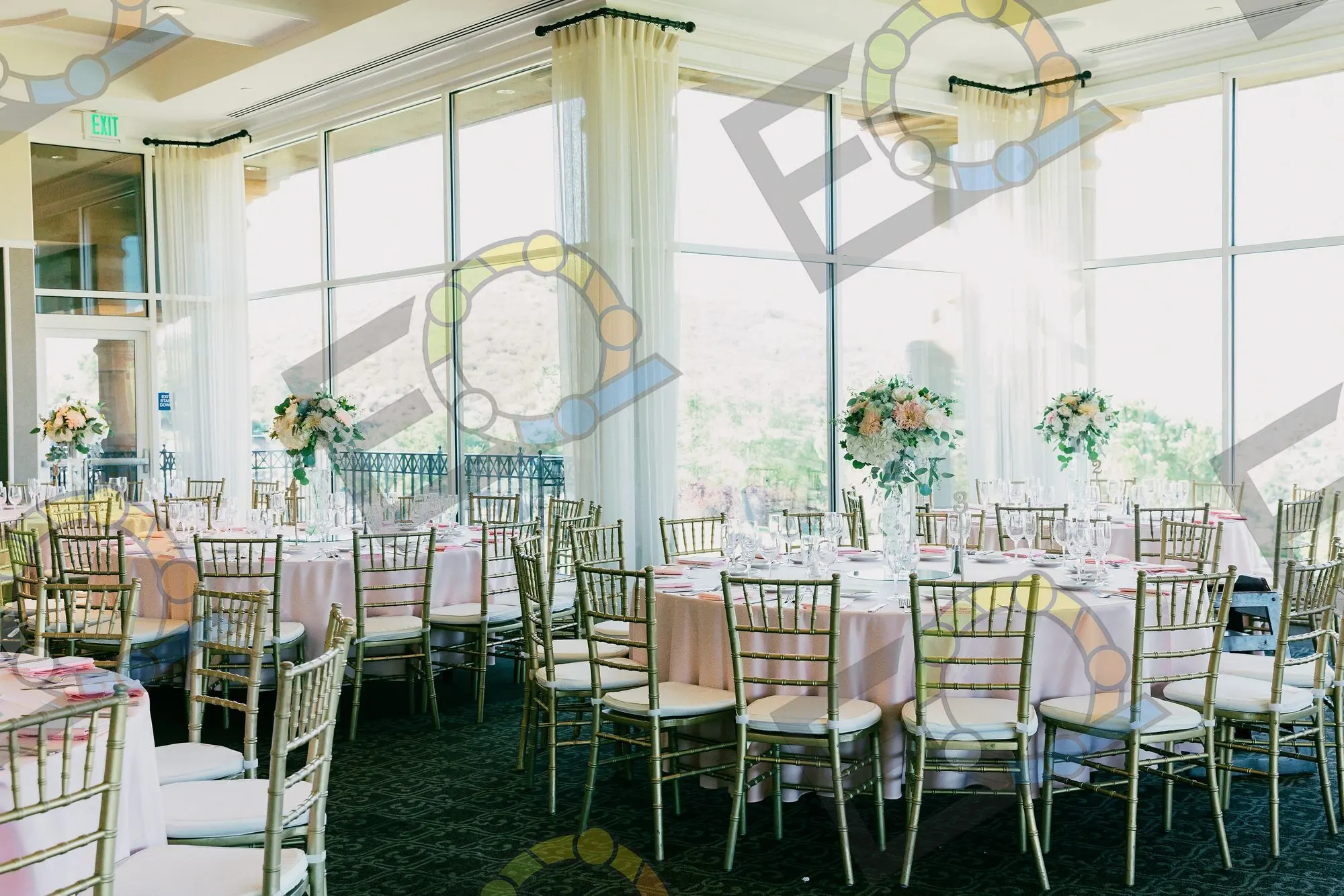 A reception room of blush-linened tables beside tall windows