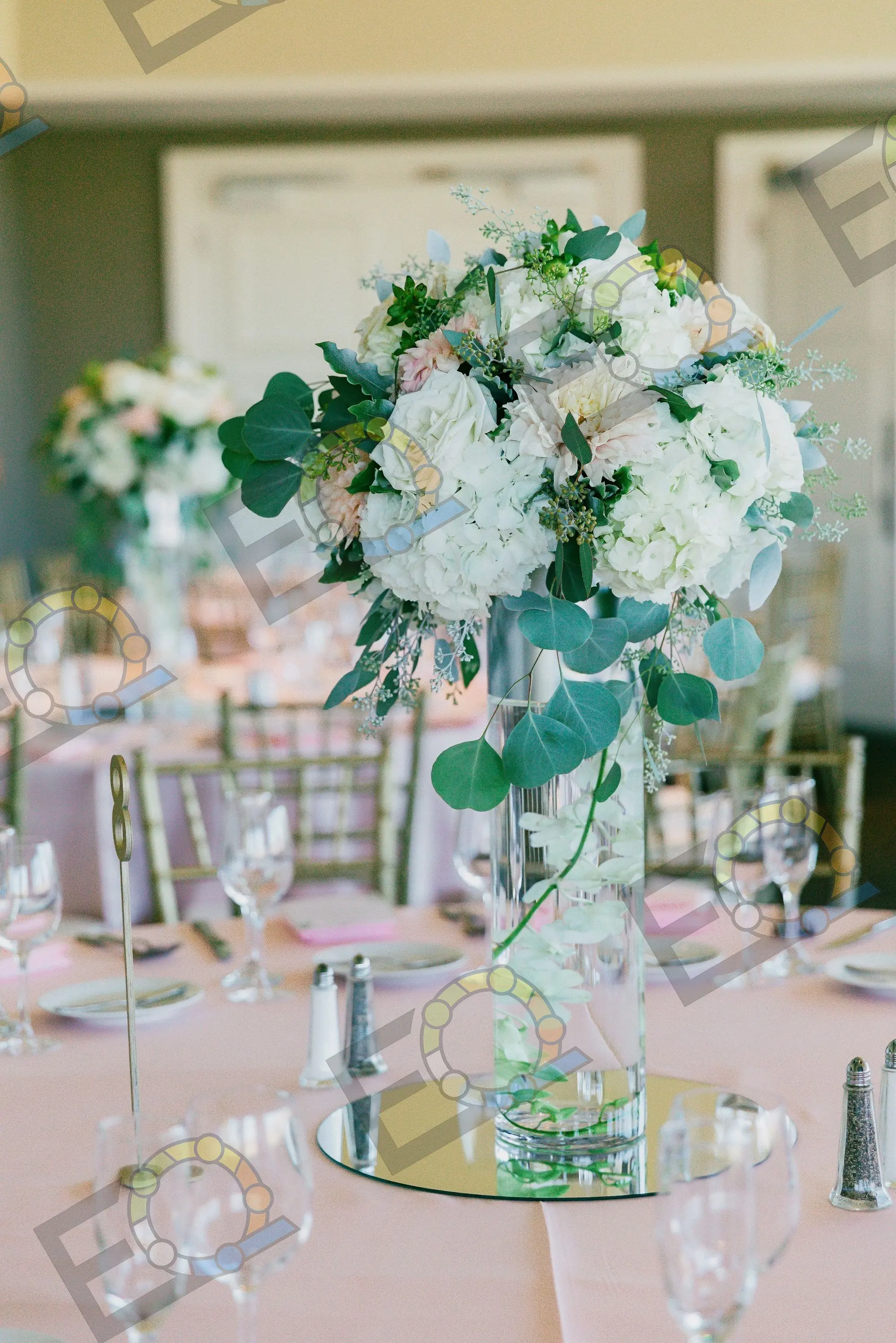 A tall hydrangea and eucalyptus centrepiece above a set table