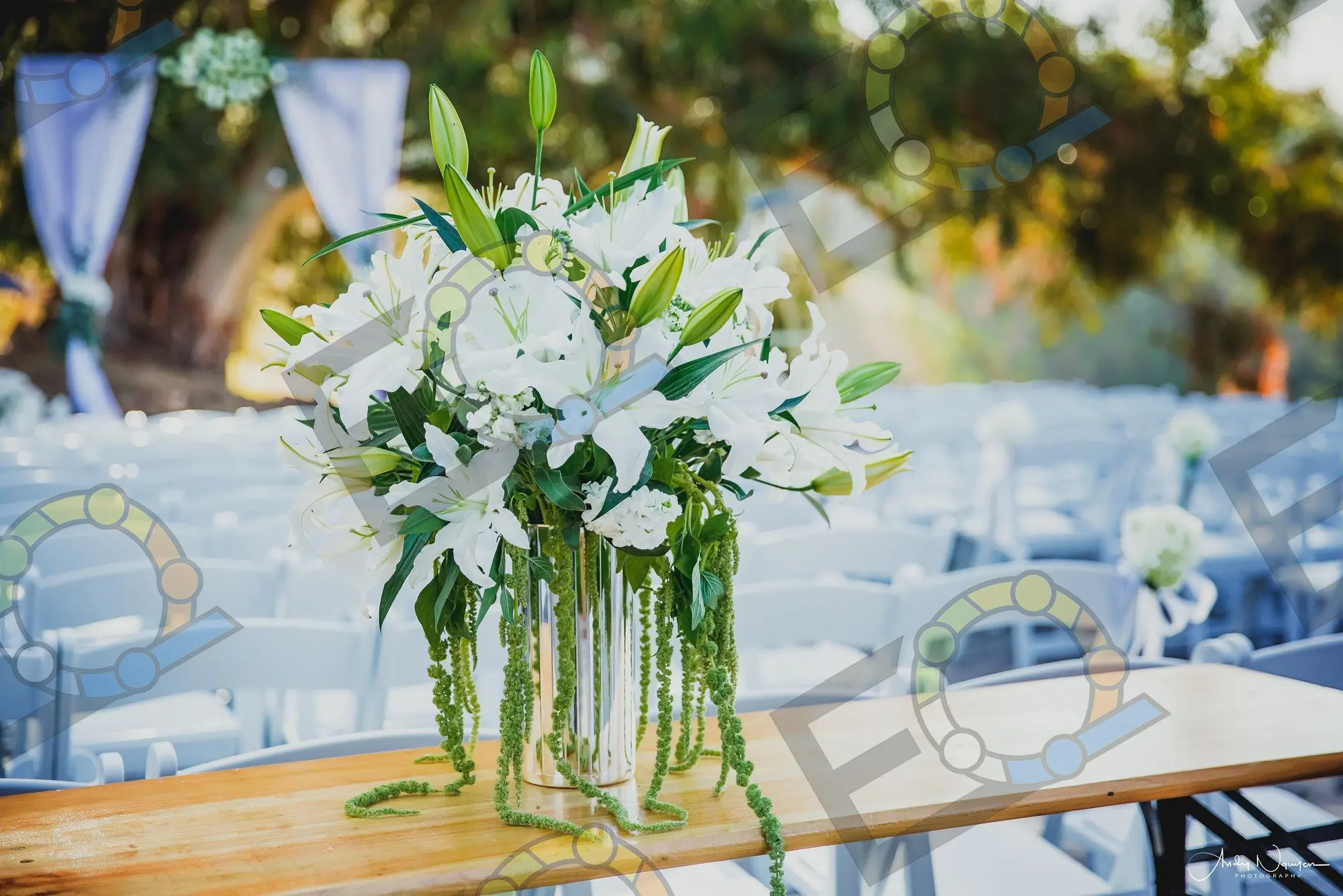 A white lily and greenery arrangement on a wooden table