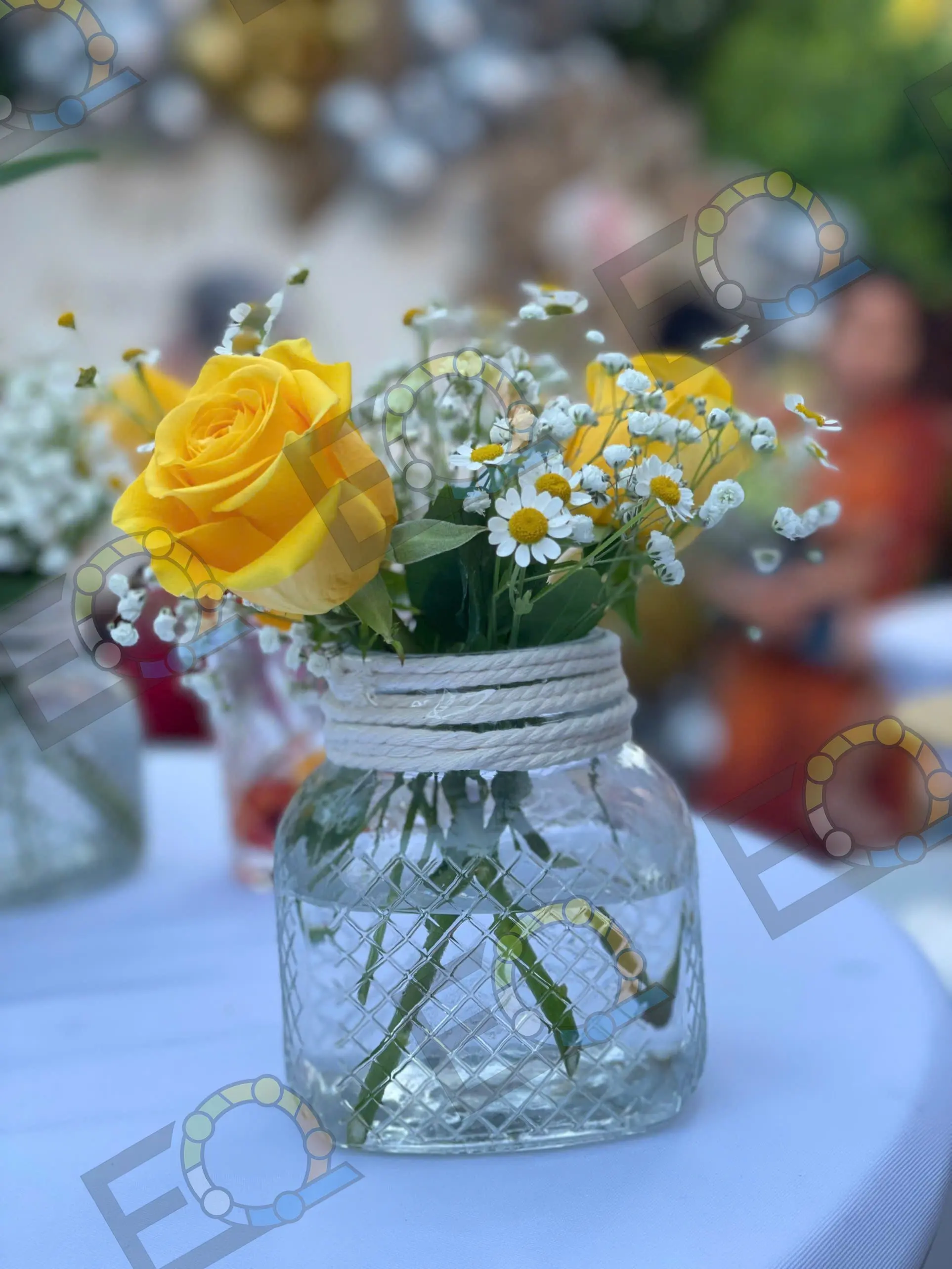 A yellow rose and daisies in a mason jar